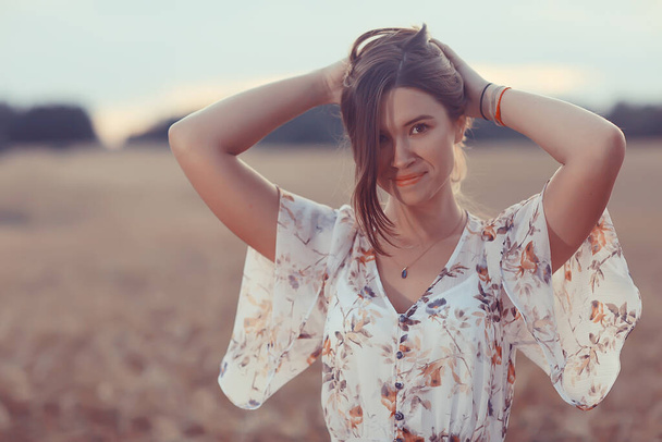 young brunette in summer with long hair in a field, happy person health beauty posing at sunset - Foto, Bild