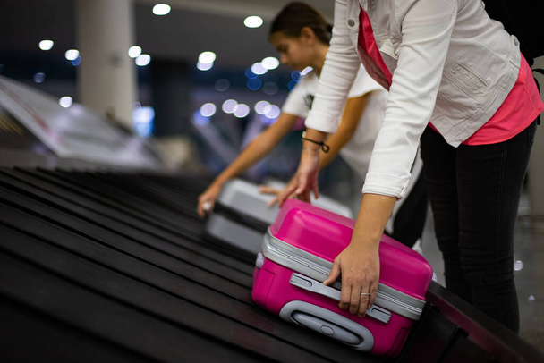Reisende, die ihren Koffer nach der Ankunft am Flughafen am Gürtel tragen, Flughafenkonzept am Kofferband  - Foto, Bild