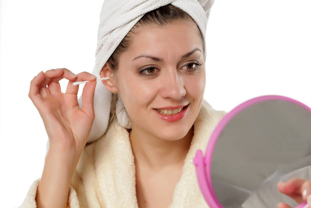 όμορφη νεαρή γυναίκα καθαρίζει τα αυτιά της με βαμβάκι - Φωτογραφία, εικόνα