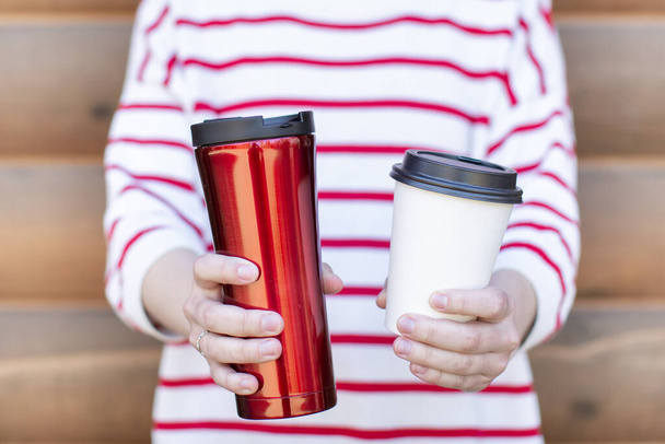 woman holding takeaway coffee cup in both hands, one is a single use paper cup with plastic lid the other one is a reusable stainless tumbler. no to plastic, No straw, 0 waste  - Foto, Bild