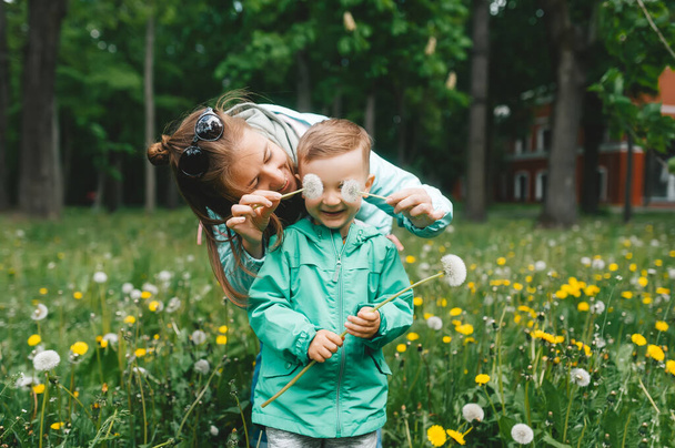 Відносини матері та синів, граються з кульбабами в парку. Син і мама з квітами кульбаби. Перегляд крупним планом
 - Фото, зображення