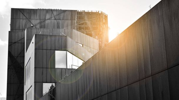 Moderno edificio de oficinas de pared de acero y vidrio con cielo azul. Superficie de vidrio con luz solar. Blanco y negro
. - Foto, imagen