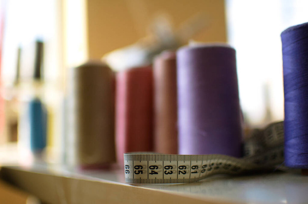 Muutama kiekot ompelulanka eri värejä pöydälle
 - Valokuva, kuva