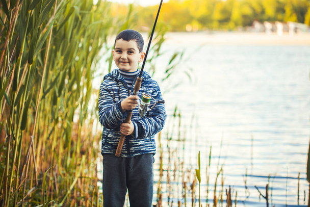 Cute boy catches fish on a summer lake. - Φωτογραφία, εικόνα