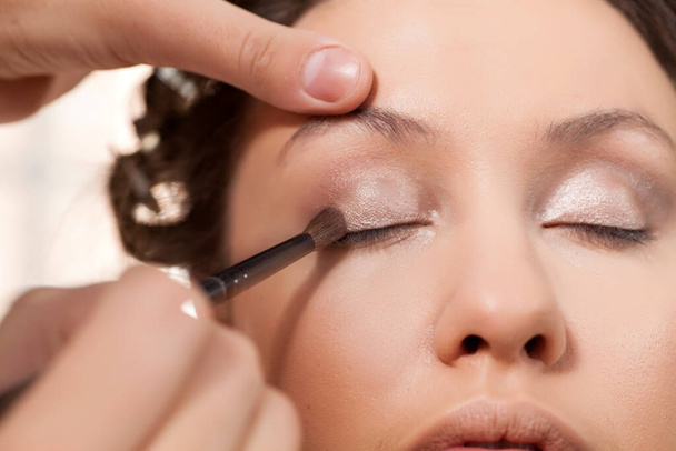 maquillador aplica sombra de ojos en el ojo del cliente
 - Foto, Imagen