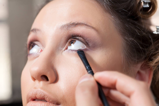 maquillador aplica sombra de ojos en el ojo del cliente
 - Foto, imagen