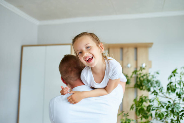 Ojciec i córka w bieli spędzają czas w domu, przystojny mężczyzna bawiąc się ze swoją małą słodką dziewczynką, relaksując się spędzając razem czas, Happy Father 's Day. - Zdjęcie, obraz