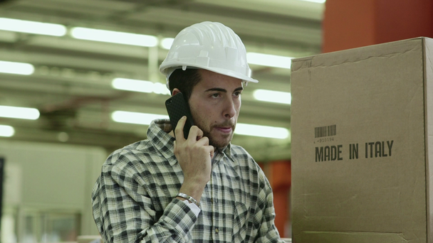 Portret van een jonge man die werkzaamheden in loondienst in logistiek faciliteit praten op mobiele telefoon - Video