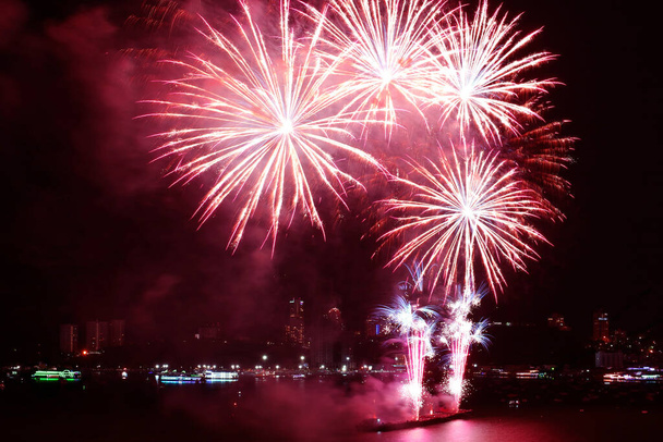 Fantastic red fireworks splashing in the night sky over the harbor - Photo, Image
