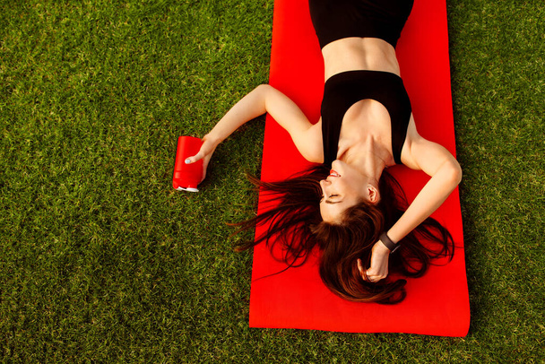 молодая женщина расслабляется после тренировки в парке
 - Фото, изображение