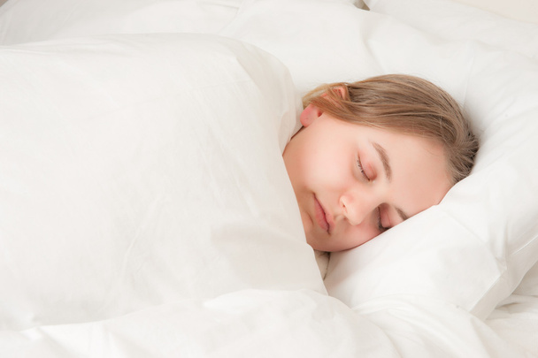 Νεαρή γυναίκα κοιμάται στο κρεβάτι - Φωτογραφία, εικόνα
