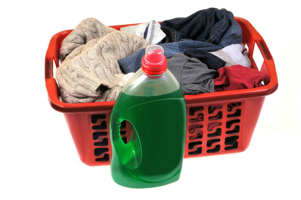 Lata de detergente líquido ao lado de uma cesta de roupa suja close-up no fundo branco
 - Foto, Imagem