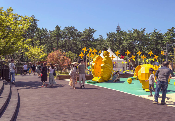 Busan, South Korea, September 14, 2019: people relaxing and walking in Songdo sky  park with yellow pinwheels and other decor on children playground - Φωτογραφία, εικόνα