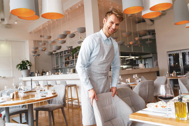 Joyful male waiter in apron working in restaurant - Fotoğraf, Görsel