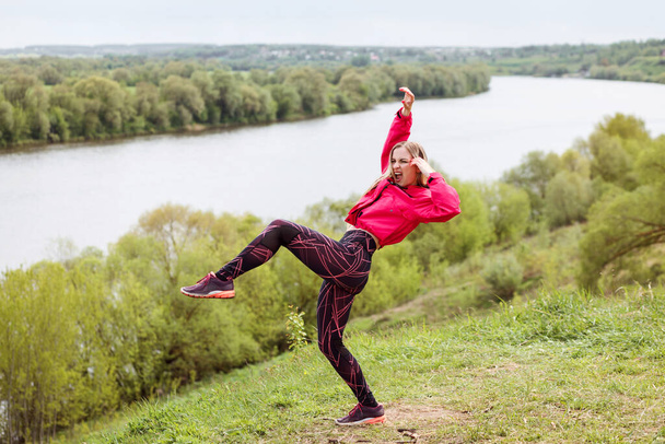 Expressive woman is dancing outdoors on the bank of the river. - Foto, afbeelding