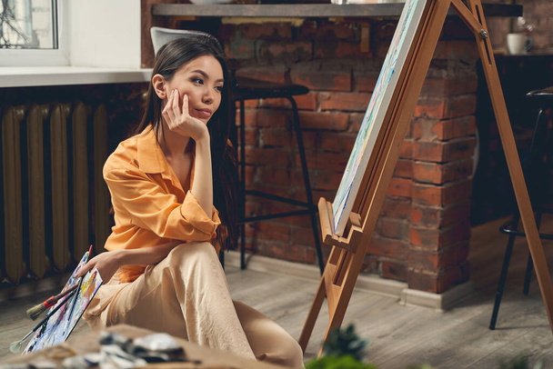 Houkutteleva nainen katselee hänen maalauksensa kotona taidestudio
 - Valokuva, kuva
