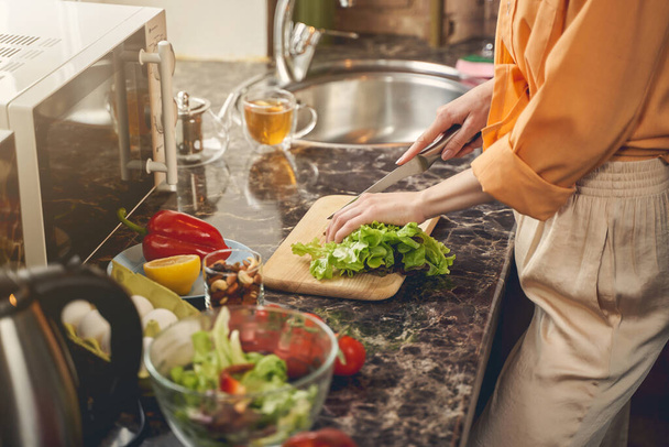 Young woman hands cutting lettuce with knife in kitchen - Foto, immagini