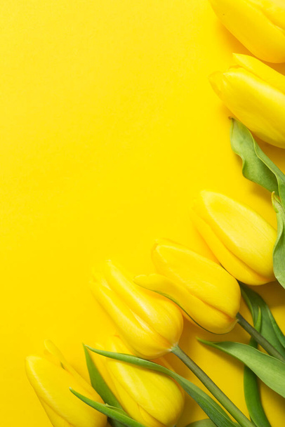 yellow tulips and paper on yellow background with space for your text - Foto, Imagen