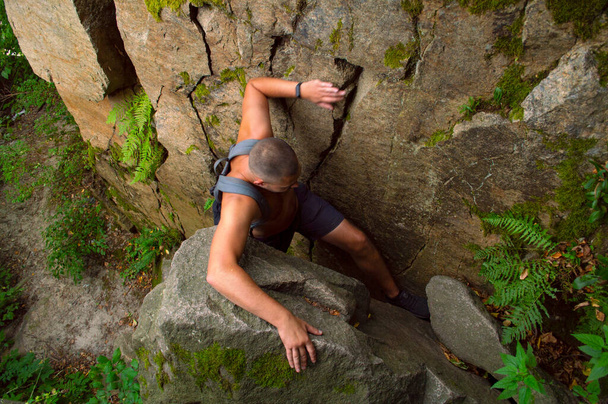 Δυνατός άντρας υψώνεται ανάμεσα στους βράχους - Φωτογραφία, εικόνα
