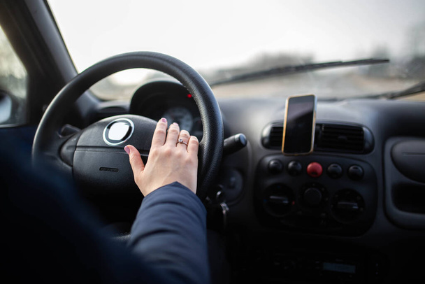 Female hands of the driver on the steering wheel while riding - Foto, afbeelding
