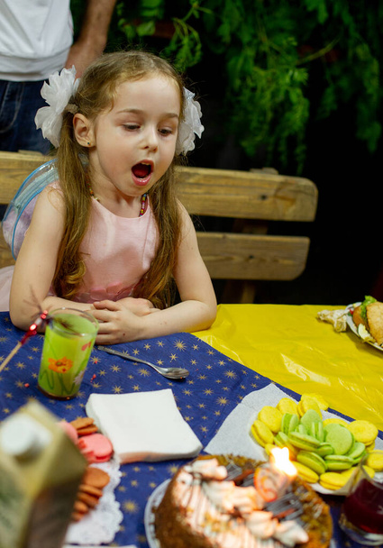 Śmiejąca się dziewczynka w wieku 5-6 lat jedząca urodziny. Dzieciństwo. Dziewczyna 5 lat urodziny. - Zdjęcie, obraz