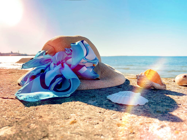 kesällä ranta naisten hattu sininen rusetti hiekalla ja simpukka horisontissa meri ja taivas auringonvalo  - Valokuva, kuva