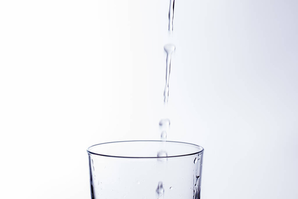 El agua clara y potable cae en un vaso transparente, sana, sana y fresca, sin olor ni sabor. Salpicadura de gotas de agua salpicando en la superficie. Jet de agua entrando en el vidrio
 - Foto, imagen