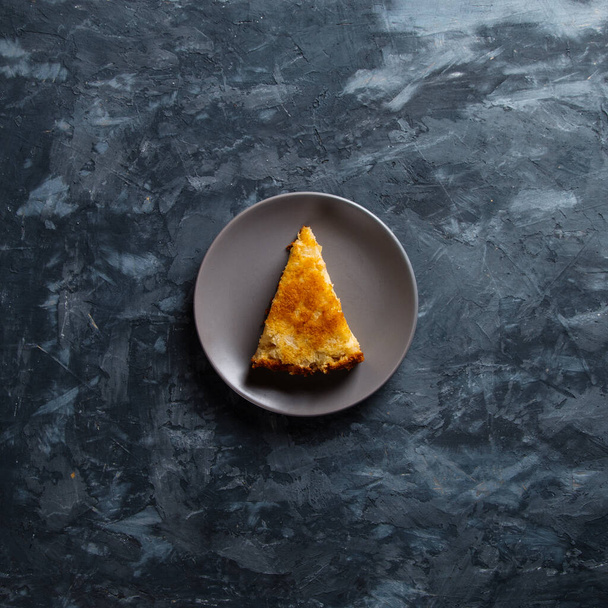 A piece of apple pie on a gray plate, against concrete background. - Foto, Imagem