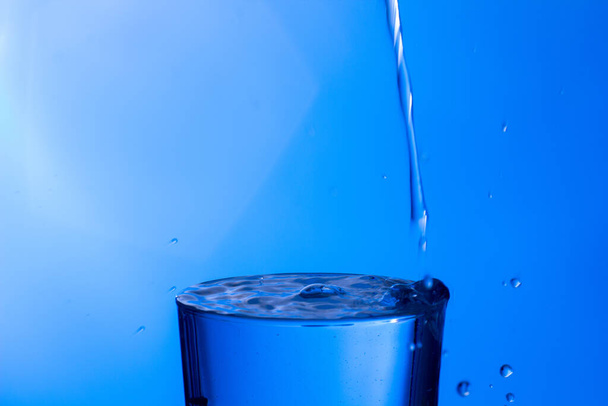 L'acqua limpida e potabile cade in un bicchiere trasparente, sana, sana, fresca e priva di odore o sapore. Spruzzi di gocce d'acqua che schizzano sulla superficie. Jet di acqua che entra nel vetro
 - Foto, immagini