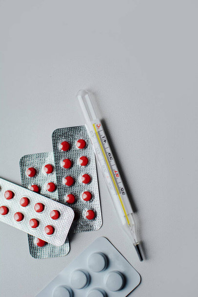 gekleurde pillen en medische thermometer op witte achtergrond close-up - Foto, afbeelding