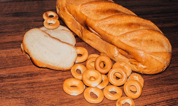 produkty piekarnicze chleb pszenny i okrągłe bajgle na brązowym drewnianym stole - Zdjęcie, obraz