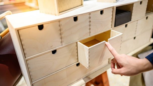 Male hand pulling and opening drawer on wooden cabinet. Home furniture and decoration shopping concept - Foto, Bild