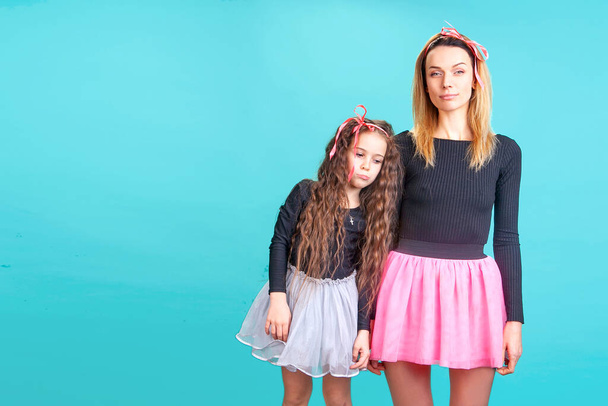 mother with daughter in black golf and short skirts express emotions in the studio on a blue background - Foto, Imagen