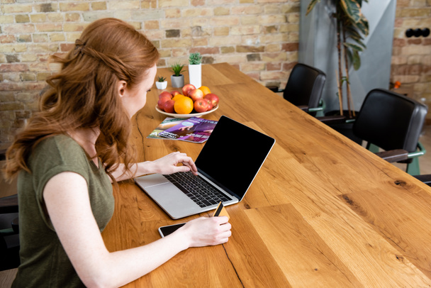 Vista lateral do freelancer usando laptop enquanto segura o cartão de crédito na mesa
  - Foto, Imagem