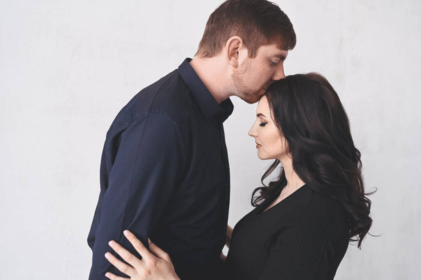 Pregnancy and people concept - happy man hugging his beautiful pregnant wife at home. Future parents waiting unborn baby. Love, relationship, birth, happy family concept - young lovely married couple - Photo, image