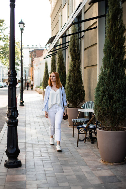 young red-haired Woman walking in city street vertical - Φωτογραφία, εικόνα