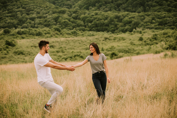 Happy young couple in love walking through grass field - 写真・画像
