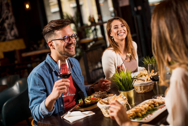 Skupina spokojených mladých lidí večeří v restauraci - Fotografie, Obrázek