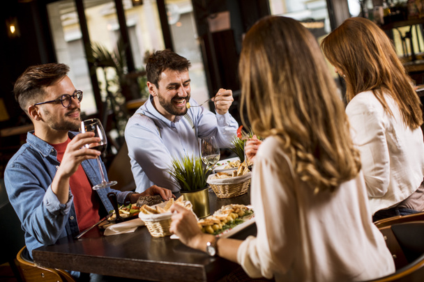 Gruppe glücklicher junger Leute beim Abendessen im Restaurant - Foto, Bild