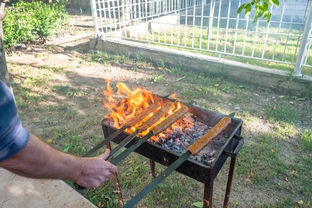 Traditional Turkish Adana  Kebap on the grill with skewers  for dinner. Turkish cuisine food culture in Turkey. Adana kebab on the mangal in nature. Picnic. - Photo, Image