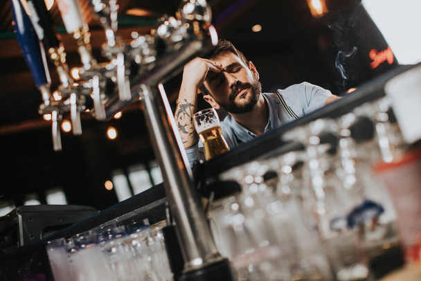 Nuori mies juo olutta ja polttaa tupakkaa pubissa yökerhossa
 - Valokuva, kuva