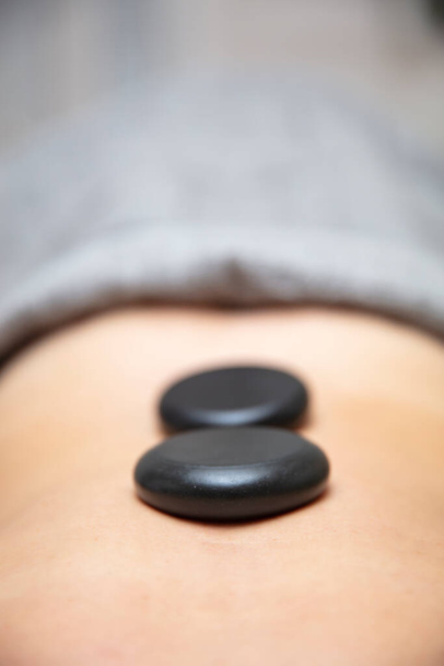 Mladá žena mají zdraví lázně relaxační kámen terapie s horkými sopečnými kameny na zádech - Fotografie, Obrázek
