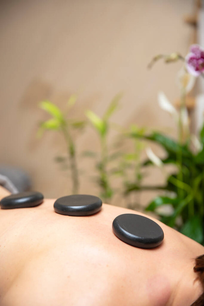 Young woman have a health spa relaxing stone therapy with hot volcanic stones on back - Fotó, kép