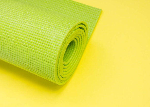 Зелёный коврик для занятий йогой свернут. Международный день йоги 21 июня. любите йога.Спорт в помещении
. - Фото, изображение