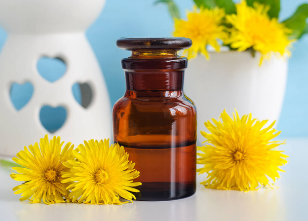 Apothecary bottle with herbal tincture (infusion, essential oil, extract) and dandelion flowers close up. Aromatherapy, homemade spa and herbal medicine concept. Copy space. - Foto, Imagem