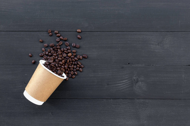 χάρτινα φλιτζάνια καφέ και φασόλι σε μαύρο ξύλινο φόντο. πάνω όψη - Φωτογραφία, εικόνα