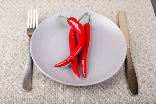 Gray plate with chilli red pepper on , spoon and knife on linen tablecloth top view - Fotó, kép