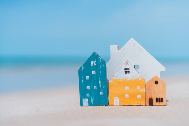 Small home model on sand beach with blue sky and white clouds background. Copy space of family lifestyle and business real estate concept. Vintage tone filter effect color style. - Photo, Image