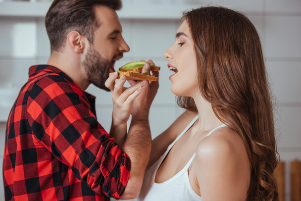 若いカップルが新鮮なアボカドでトーストを食べ - 写真・画像