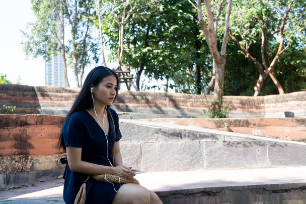 Длинные волосы женщина сидит одна на скамейке в парке, она грустно, что ее парень отменить встречу
. - Фото, изображение